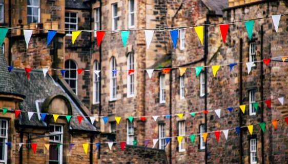Brightly coloured bunting hangs in front of multi-level stone houses