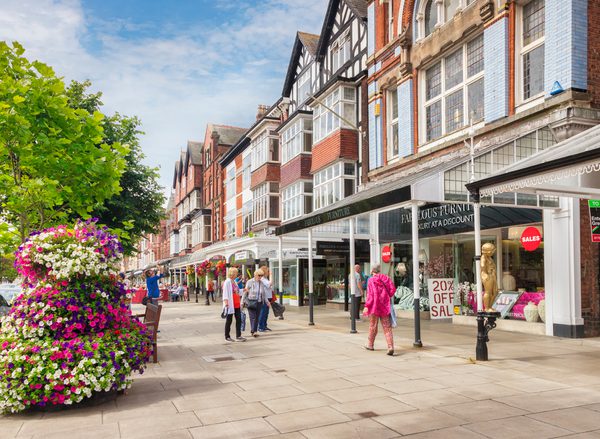 Southport high street on a sunny day. A colourful selection of people out shopping and some planters full of flowers