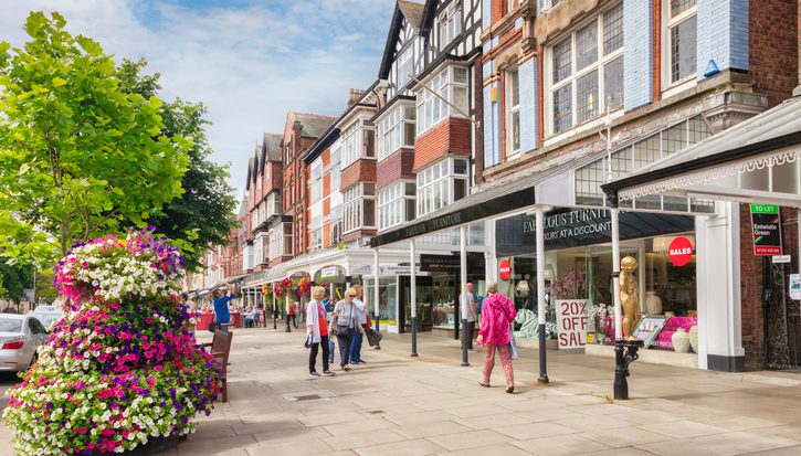 Southport high street on a sunny day. A colourful selection of people out shopping and some planters full of flowers