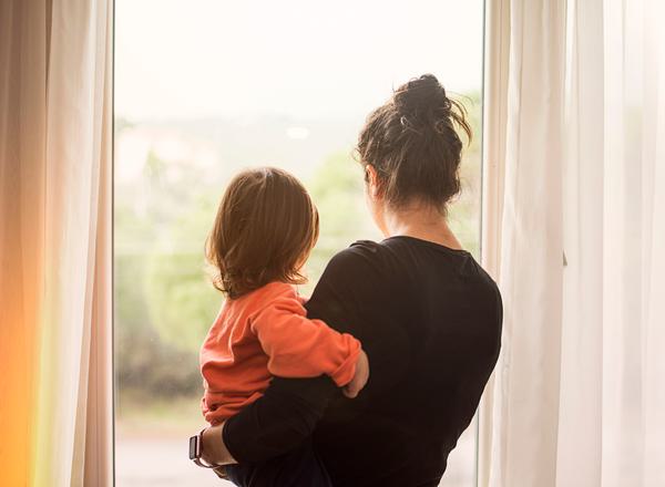 A mother and child from behind looking out of a window