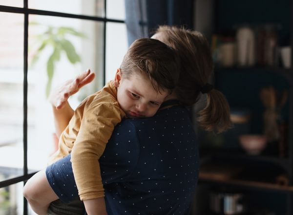 A mother comforts her sone while looking out of a window
