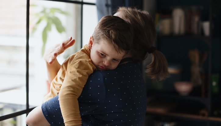 A mother comforts her sone while looking out of a window
