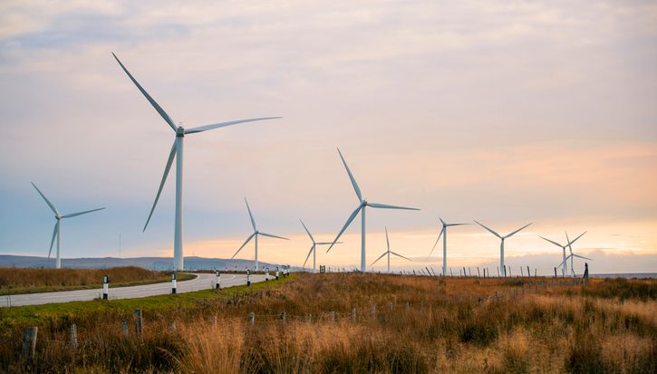 A beautiful sunset in the Scottish highlands with renewable energy wind turbines far into the horizon