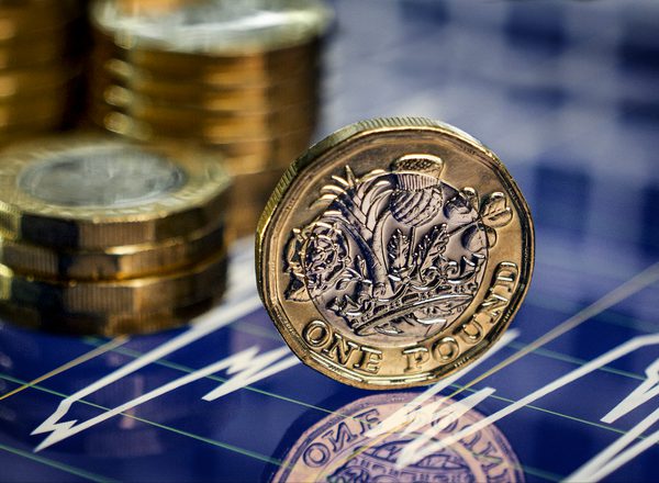 Graphic depicting a stack of pound coins in the background and one sideways pound coin displayed on its side in the foreground