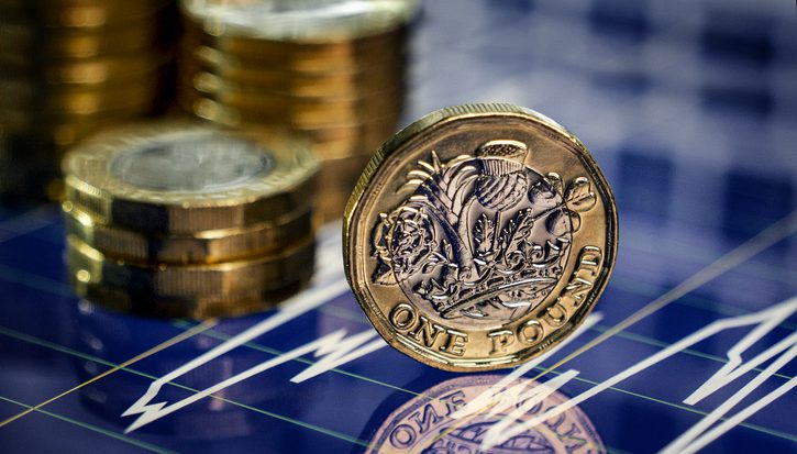 Graphic depicting a stack of pound coins in the background and one sideways pound coin displayed on its side in the foreground