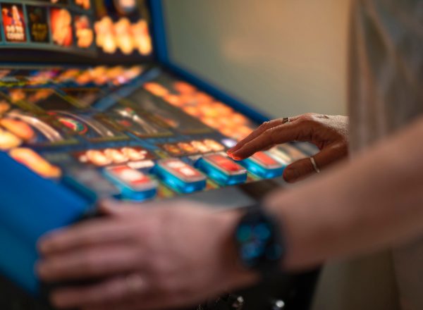 An unrecognisable woman playing a slot machine in a social club