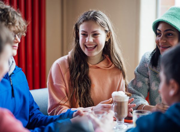 A group of young women laughing sitting around a cafe table