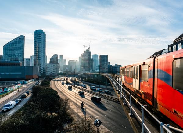 Train and cars on a motorway with London skyline in background
