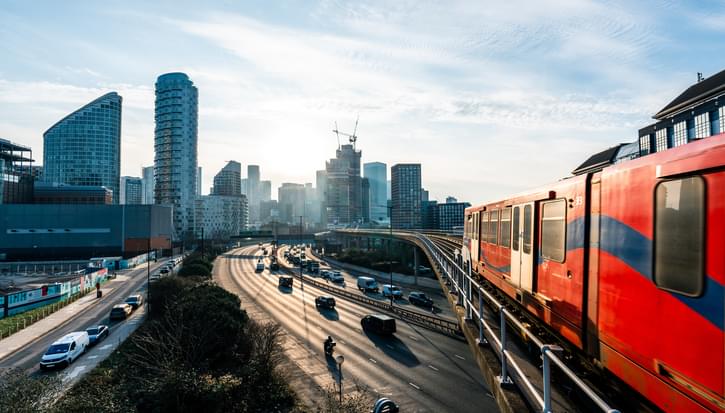 Train and cars on a motorway with London skyline in background