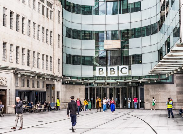 The outside of the BBC building in London with people walking in front of it