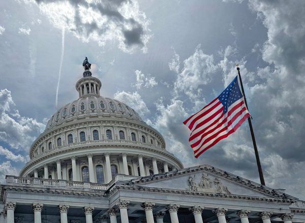 The White House in Washington DC, cloudy skies and US flag