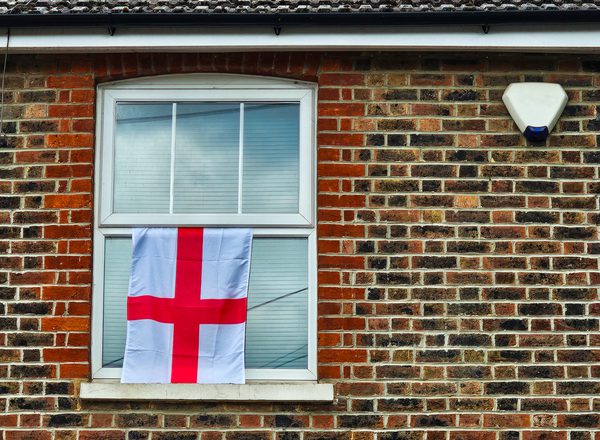 A close-up photo of a house flying an England flag from an upstairs window