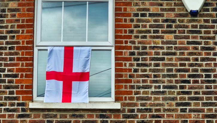 A close-up photo of a house flying an England flag from an upstairs window