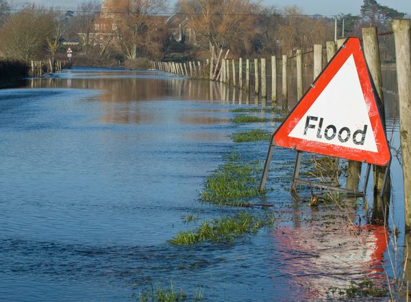A flood warning sign, on a closed country road next to water logged fields in the Avon Valley, Hampshire, England