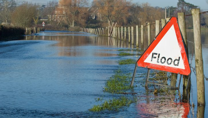 A flood warning sign, on a closed country road next to water logged fields in the Avon Valley, Hampshire, England