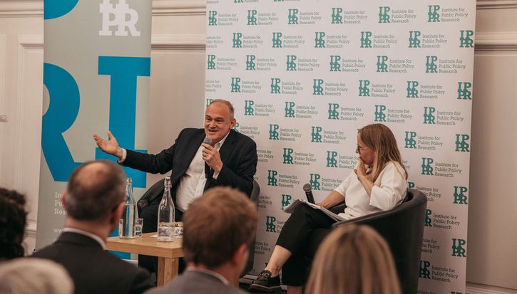 Ed Davey and Sarah Mulley sat in front of IPPR banners. Ed Davey is speaking into a microphone.