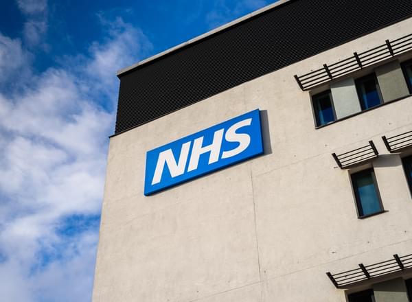 An building with the NHS logo on with a blue sky behind