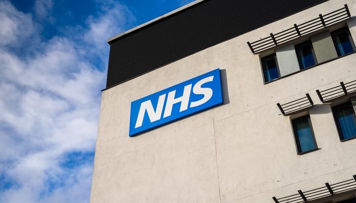 An building with the NHS logo on with a blue sky behind